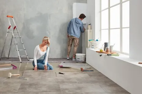 Frau und Mann renovieren ein Loft mit modernem Vinylboden in heller Betonoptik
