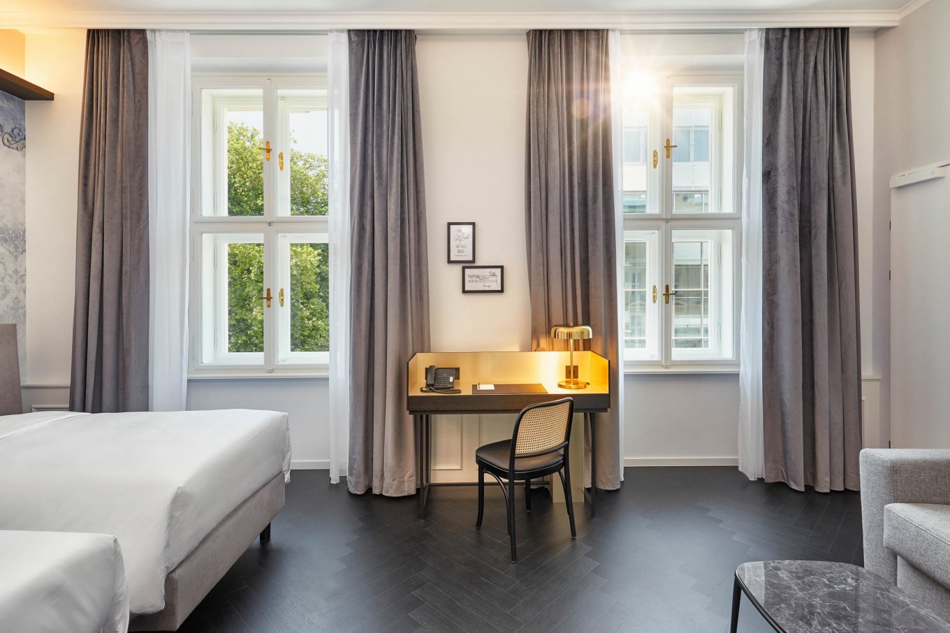 dunkler Fußboden im Fischgrätmuster verlegt im Schlafzimmer mit zwei Betten und einem Schreibtisch im Hyperion Hotel in Salzburg