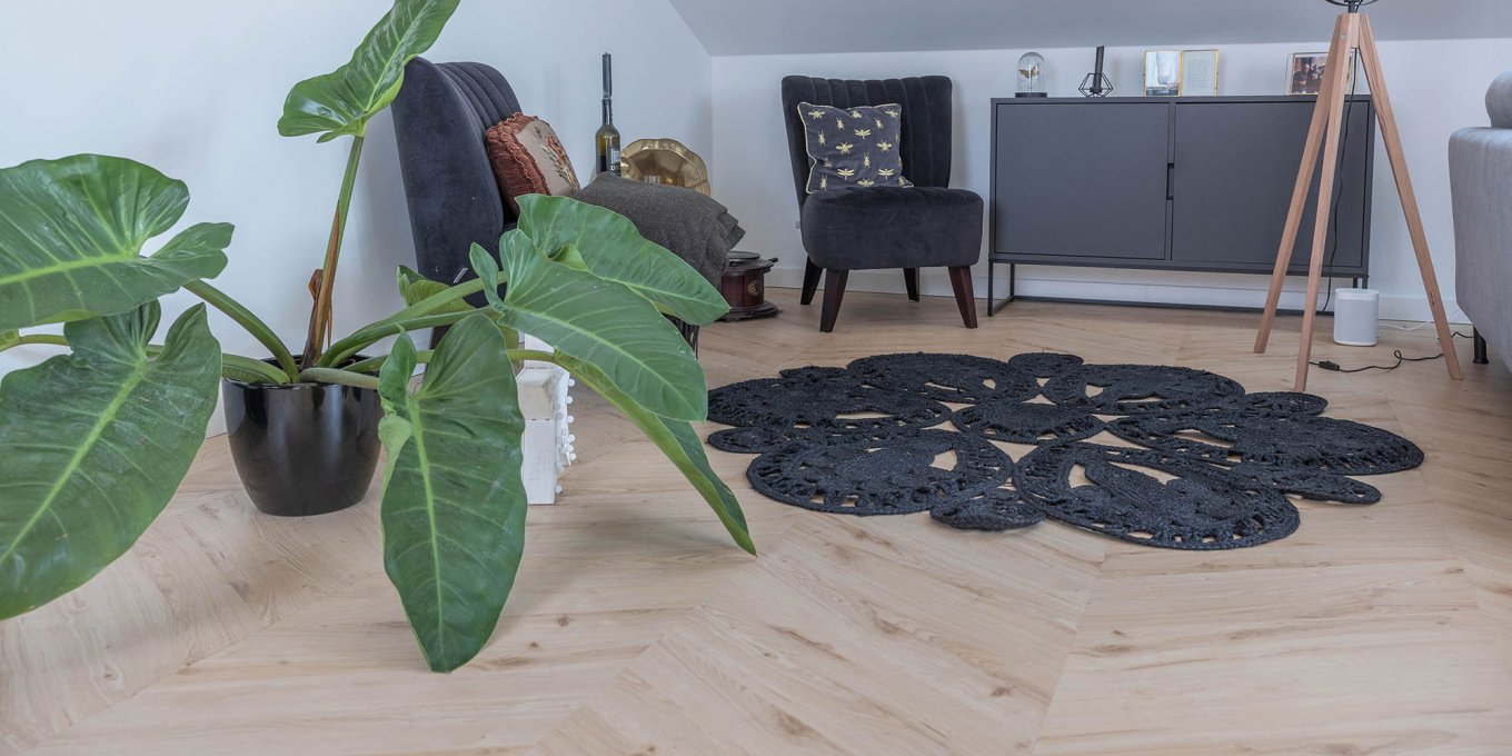 wineo PURLINE Bioboden im Wohnzimmer Holzoptik Fischgrätmuster Teppich Zimmerpflanze Sideboard