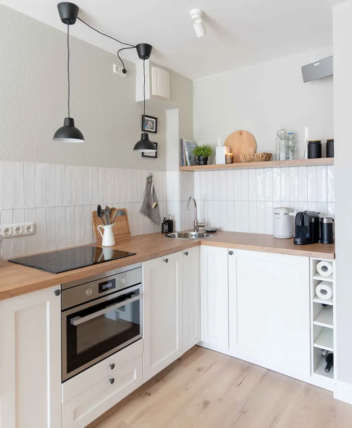 Moderne. weiße Küchenzeile mit Holzarbeitsplatte und hellem, rusitkalen Holzfußboden