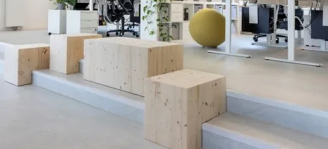 wineo PURLINE Bioboden in heller Holzoptik im Büro mit höhenverstellbaren Schreibtischen und Holzsitzbänken