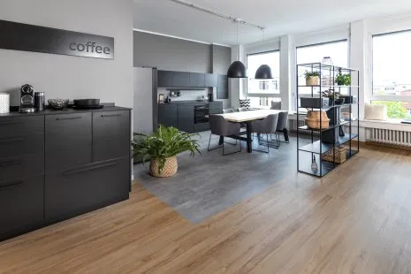 Moderne Küche mit Küchenzeile, hochwertigen schwarzen Möbeln und Fußboden in Holzoptik