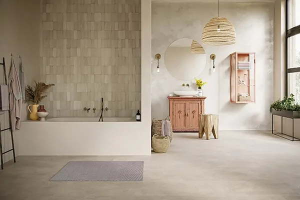 Modernes Badezimmer mit Badewanne, beigen Fliesen und hellem Betonfußboden