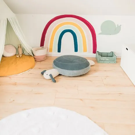 Kinderzimmer mit Wandbemalung, Kuschelkissen einem Tipi und hellem Holzfußboden