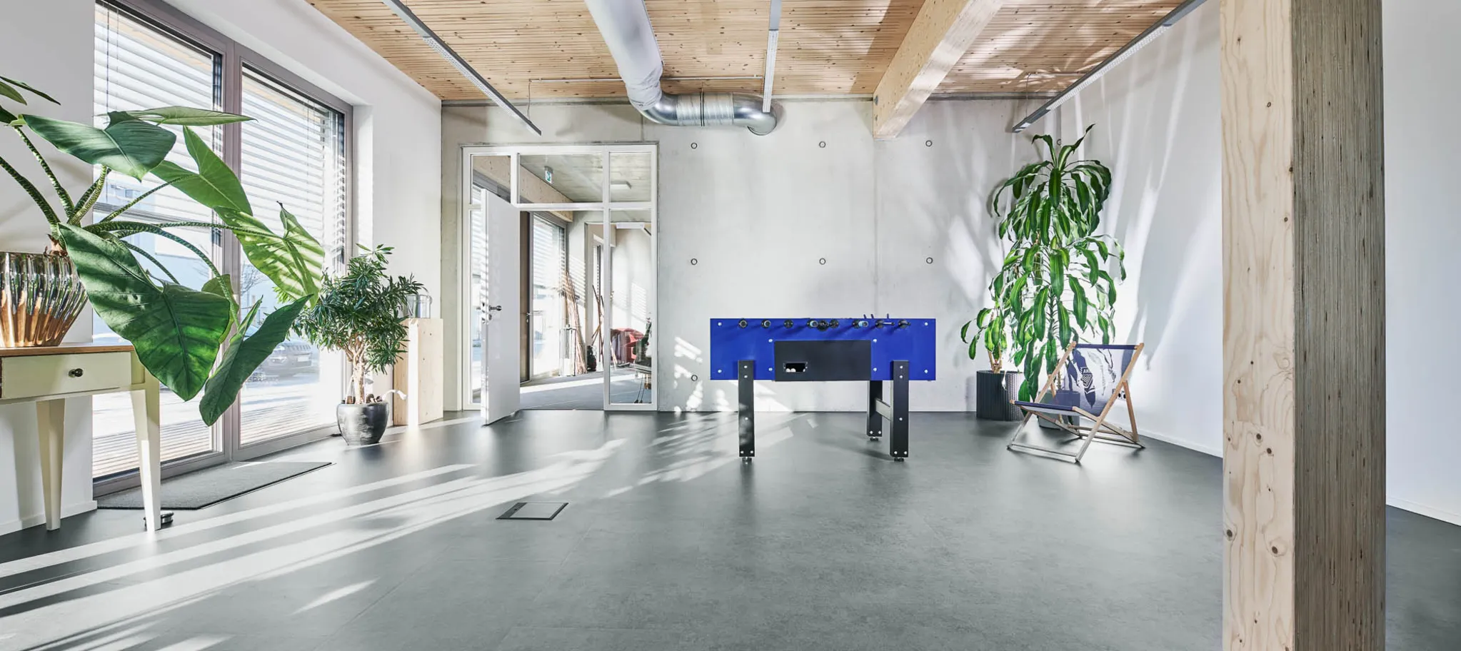 wineo PURLINE Bioboden im Büro dunkle Fliesen Tischkicker Kickertisch Zimmerpflanze Grünpflanze Fußboden Bodenbelag