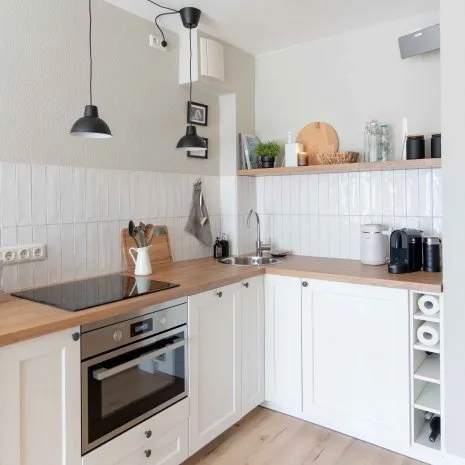Moderne. weiße Küchenzeile mit Holzarbeitsplatte und hellem, rusitkalen Holzfußboden