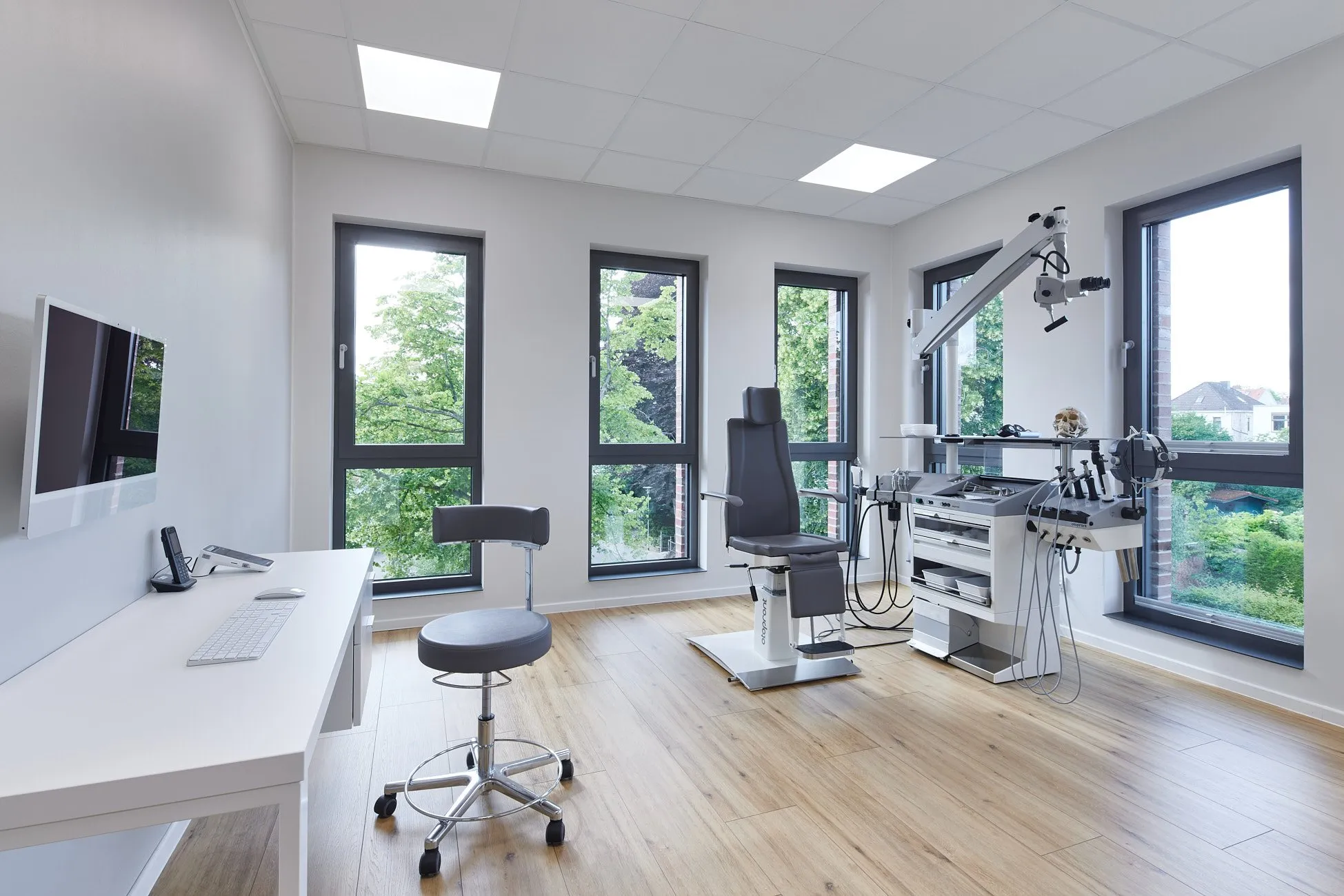 Behandlungszimmer mit Zahnarztstuhl und moderner Einrichtung auf Bodenbelag in Holzoptik